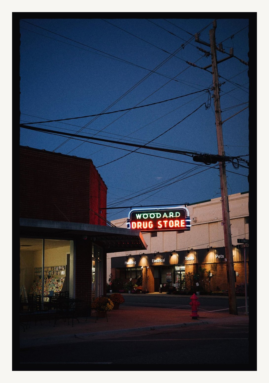 A neon drug store sign at dusk in a Filed edge